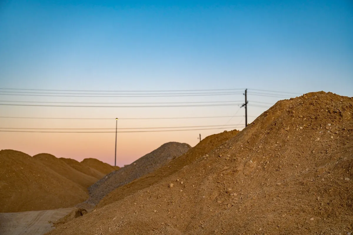Top Compact & Mini Excavator Diggers- TYPHON Machinery Mounds of soil under a colorful evening sky, highlighting the landscape's potential for small excavation projects.